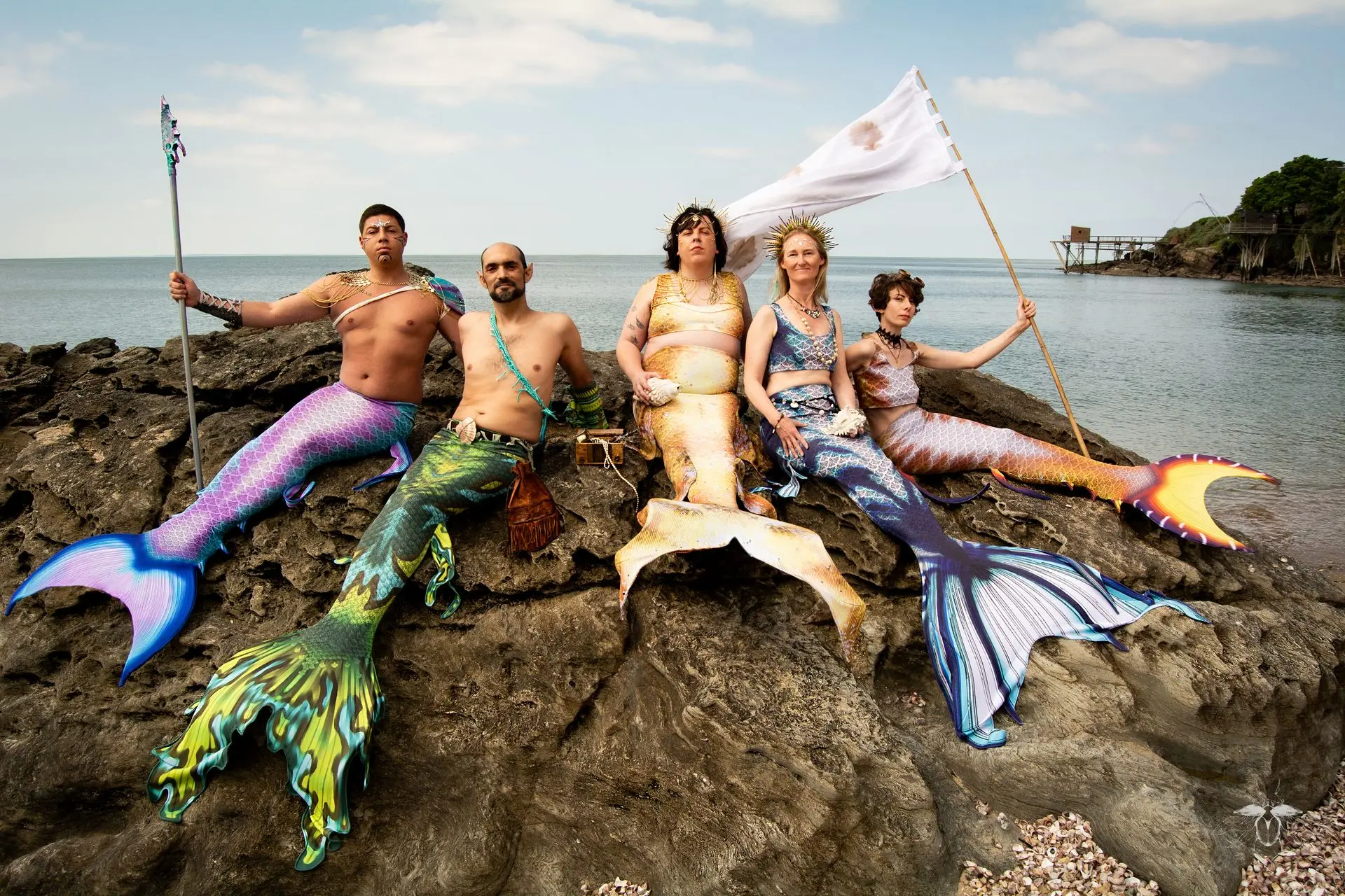 Sur un rocher à marée basse, un groupe de sirènes et de tritons entoure la reine des Océans, Mica, brandissant lance et étendard, apportant les richesses des profondeurs à la surface.
